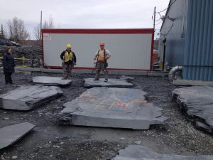 Slate quarry employees showing how they mark the stone to find the right size to cut in the plant